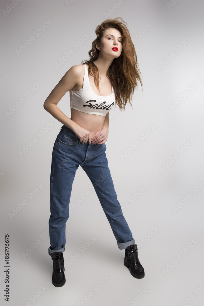 Attractive young red-haired girl in top and jeans