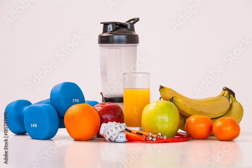 The concept of a healthy diet. Small dumbbells. Shaker. Bananas. Apples. Oranges. The skipping rope. Measuring tape waist. on a white background. healthy lifestyle. sport. Fitness food.