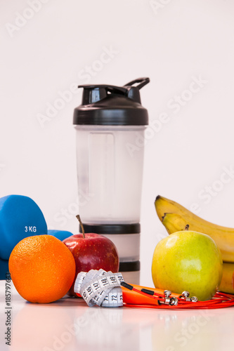The concept of a healthy diet. Small dumbbells. Shaker. Bananas. Apples. Oranges. The skipping rope. Measuring tape waist. on a white background. healthy lifestyle. sport. Fitness food. close-up