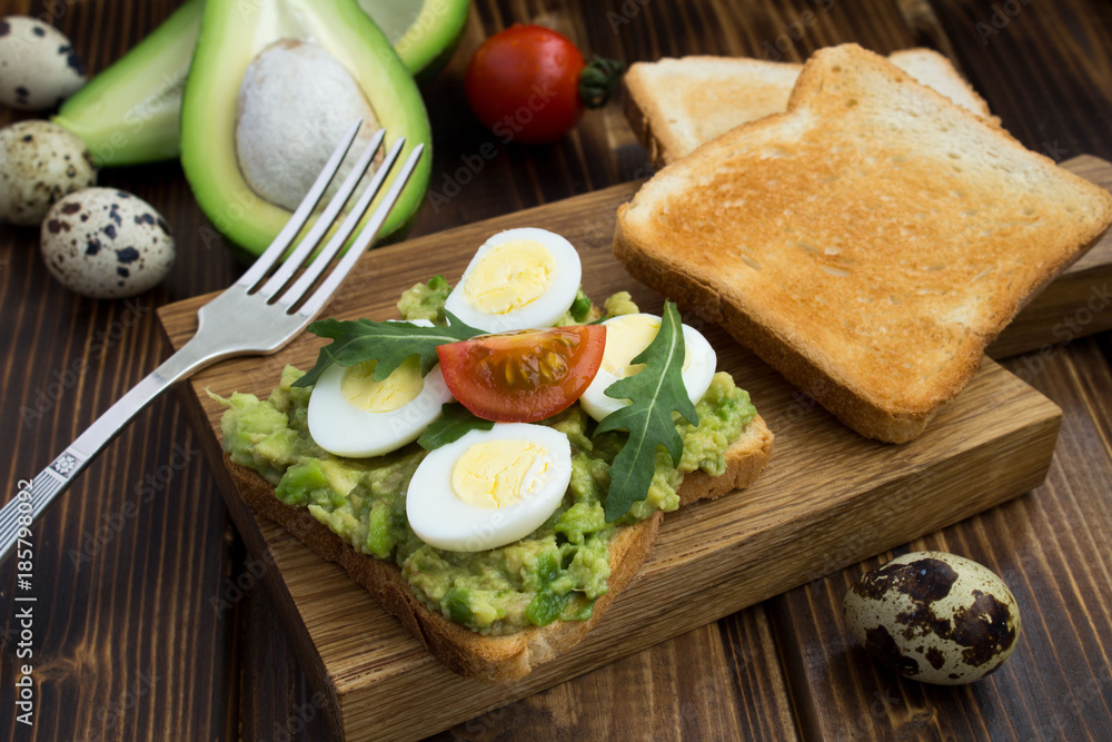 Breakfast: vegetarian sandwich with quail eggs,avocado and cherry on the wooden cutting board Breakfast: vegetarian sandwich with quail eggs,avocado and cherry on the wooden cutting board