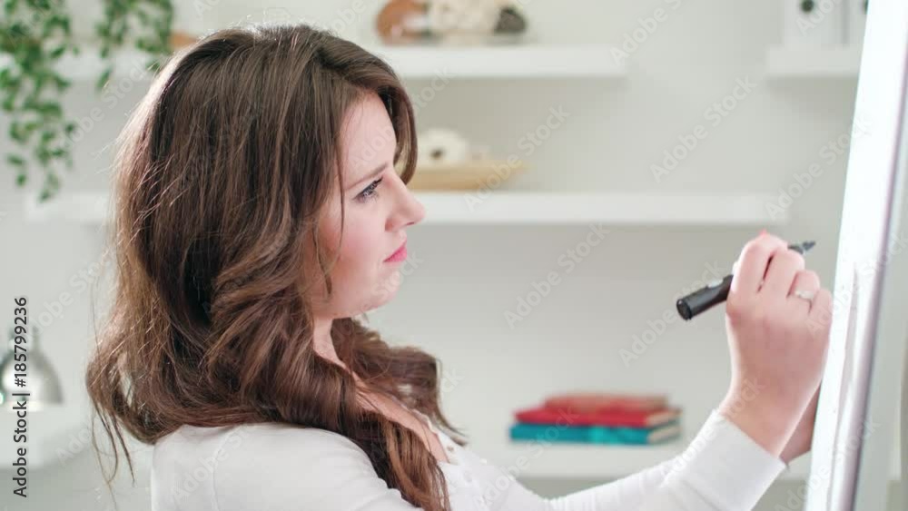 A beautiful young woman drawing on a sheet of paper in an office. Close-up Dolly shot. Soft focus. A beautiful young woman drawing on a sheet of paper in an office. Close-up Dolly shot. Soft focus.