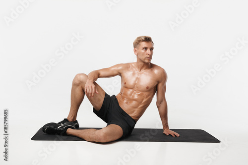 Handsome sportive man posing on mat