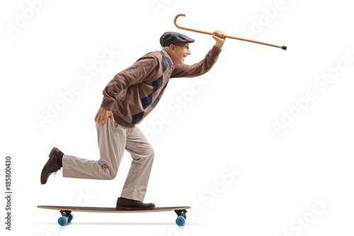 Joyful senior holding a cane and riding a longboard