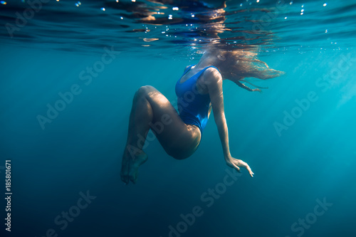 Underwater woman portrait in blue ocean with day light. © artifirsov