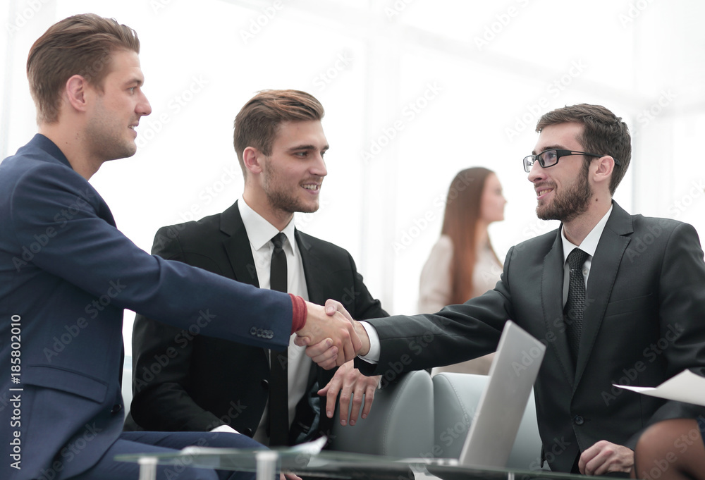 Partners concluding deal and shaking hands in the presence of team members Partners concluding deal and shaking hands in the presence of team members