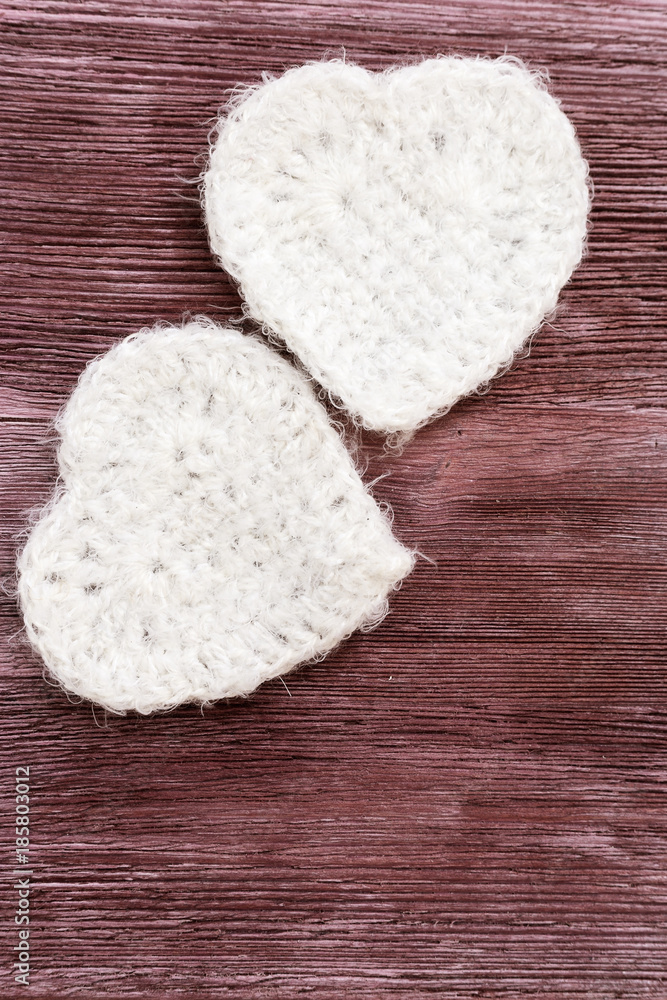 Two white hearts on old wooden background. Knitted white heart. Composition for Valentine's day or postcards. Background for congratulations with copy space. Vertical format. Two white hearts on old wooden background. Knitted white heart. Composition for Valentine's day or postcards. Background for congratulations with copy space. Vertical format.
