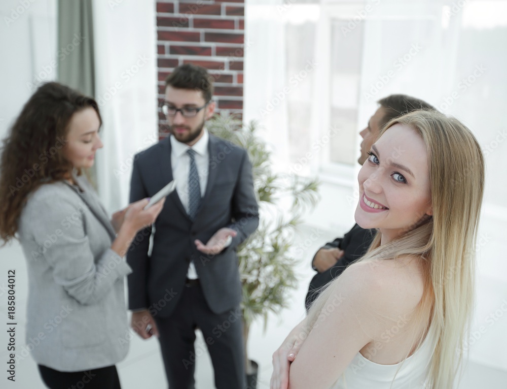 successful young woman - a company employee against the backdrop of colleagues successful young woman - a company employee against the backdrop of colleagues