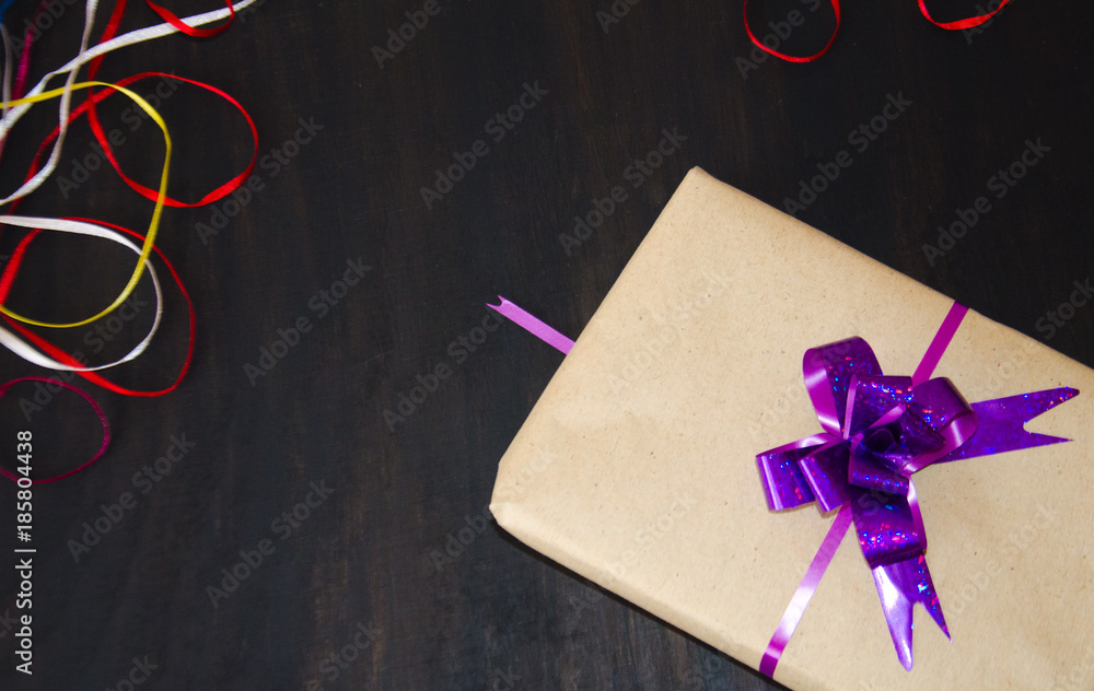 gift with a purple bow on a black wooden background gift with a purple bow on a black wooden background