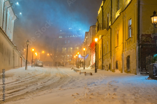 Evening in the night snowy street under snowfall