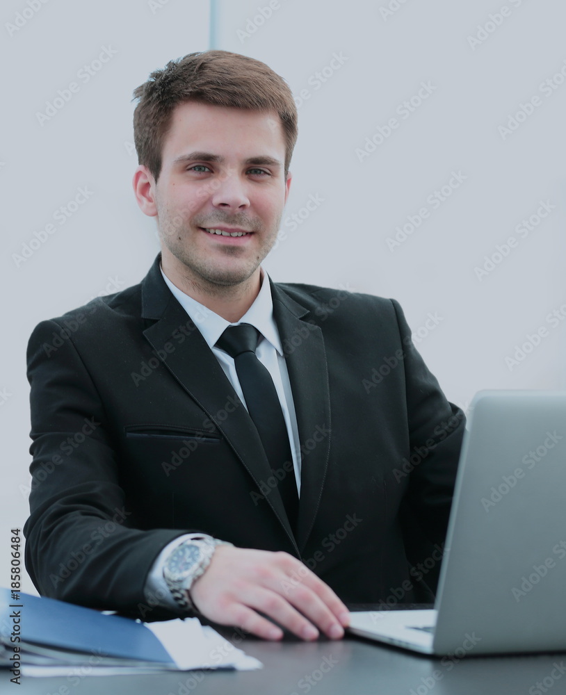 successful businessman sitting behind a Desk with an open laptop successful businessman sitting behind a Desk with an open laptop