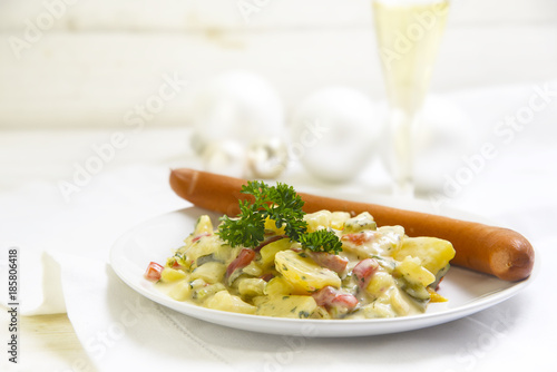 Foto potato salad with wiener sausage and parsley garnish on a white wooden table, ty