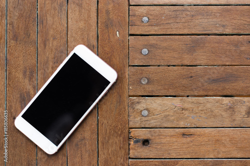 White smartphone on the old wooden background, top view