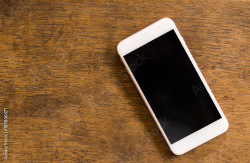 White smartphone on the old wooden background, top view