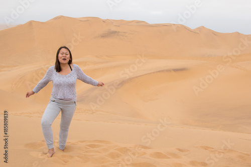 Indonesian girl posing on Dune 7 in Walvis Bay, Namibia © peterralph