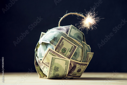 Bomb of money hundred dollar bills with a burning wick. Little time before the explosion. Concept of financial crisis photo