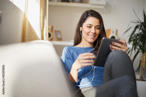 Woman playing with her dog while sitting on sofa in living room