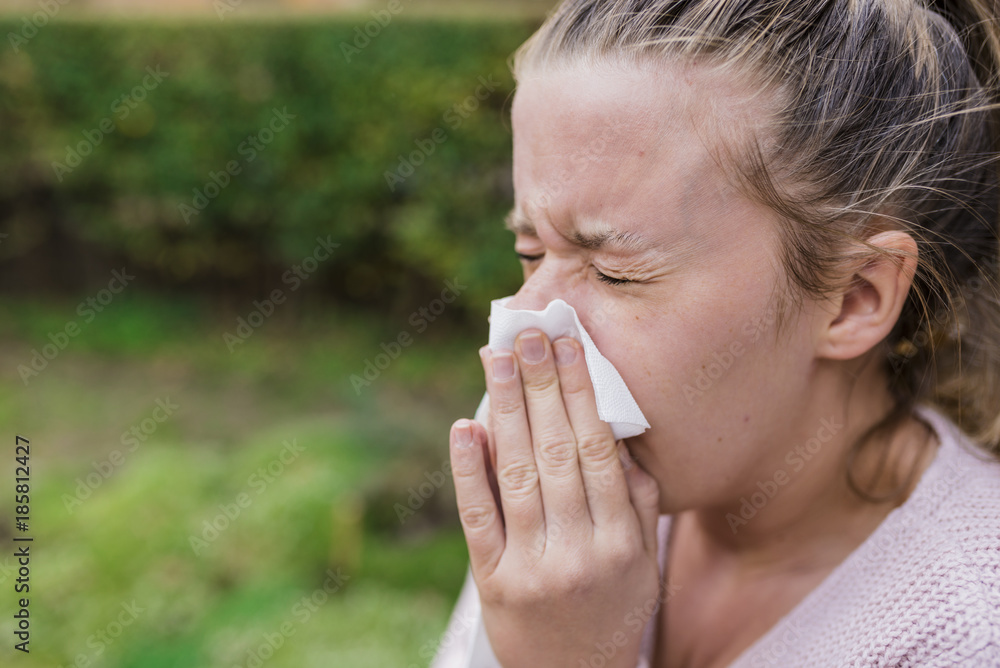 Attractive woman outdoor with tissue having allergy. Woman blowing her nose into tissue Attractive woman outdoor with tissue having allergy. Woman blowing her nose into tissue