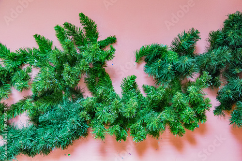 Synthetic branch of a coniferous tree on a background of a bright wall  