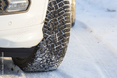 Studded winter tyre on the snow on a modern white car.  photo