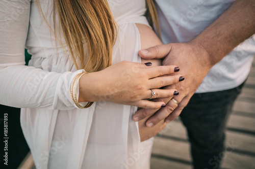 The hands of a woman and a man are placed on a pregnant belly