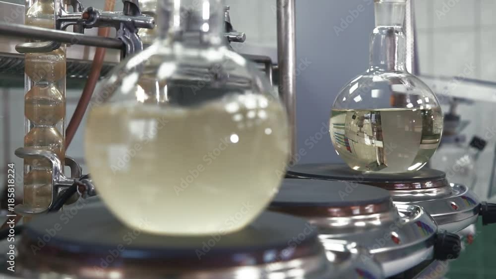 Bulb with boiling liquid close-up. Flask is heated with large temperature on the stove in laboratory. Change the focus between the foreground and background. Scientific experiment. Bulb with boiling liquid close-up. Flask is heated with large temperature on the stove in laboratory. Change the focus between the foreground and background. Scientific experiment.