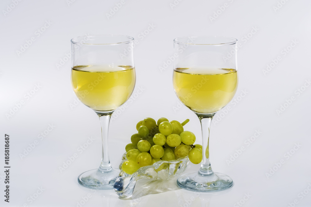 Two glasses of white wine and a bunch of green grapes on a glass plate / Picture made in the personal Studio of a photographer Two glasses of white wine and a bunch of green grapes on a glass plate / Picture made in the personal Studio of a photographer