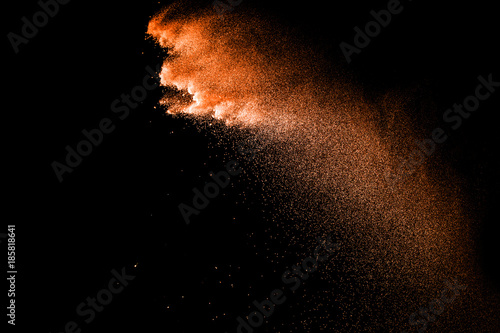 Orange particles explosion on black background. Freeze motion of orange dust splash on dark background.