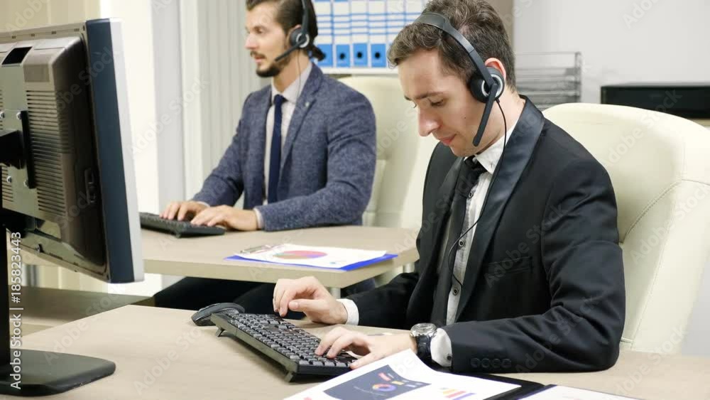Customer support line worker using headset to talk on the hot line with customers Customer support line worker using headset to talk on the hot line with customers