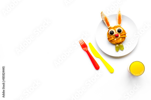 Funny breakfast for children. Meal with cheesecake in shape of hare. White background top view copyspace