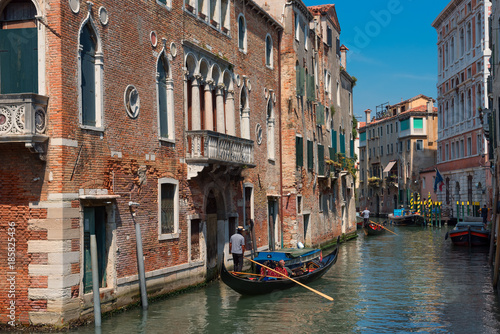 Traditional narrow canal street with gondolas and old houses in Venice, Italy. Architecture and landmarks of Venice. Beautiful Venice postcard. © djevelekova