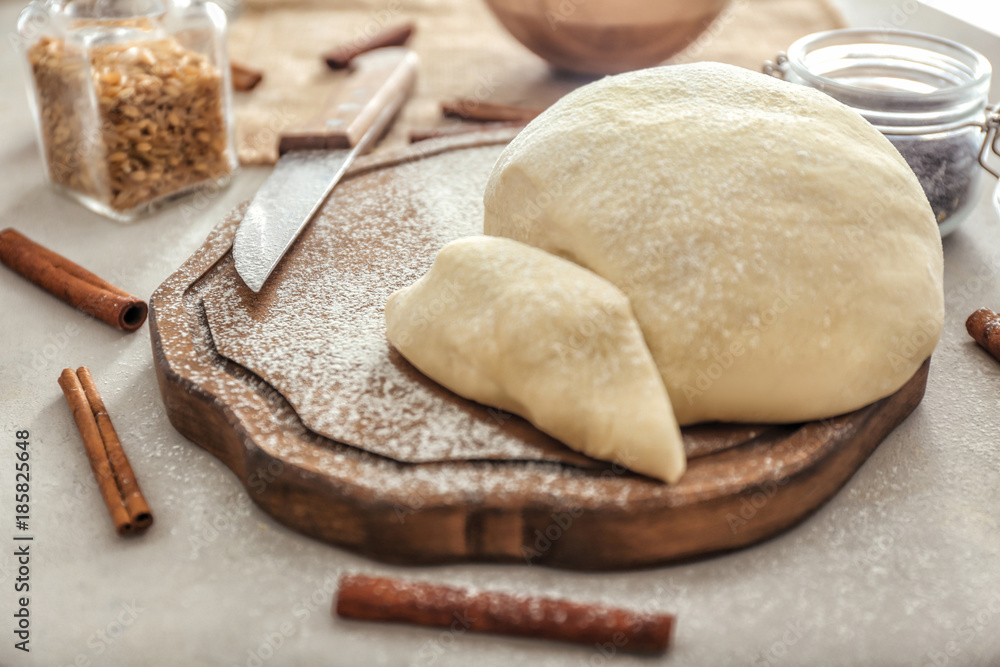 Wooden board with raw flaky dough on table Wooden board with raw flaky dough on table