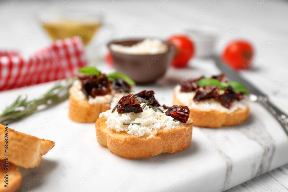 Tasty bruschetta with sun-dried tomatoes on board, closeup