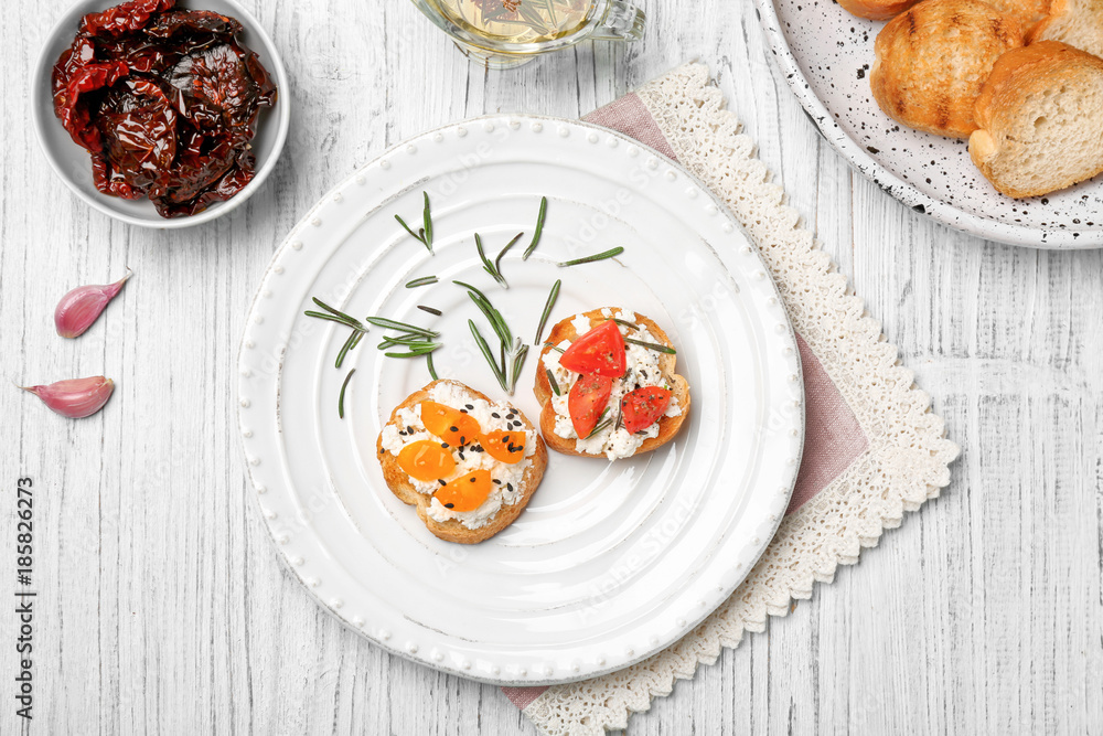 Tasty bruschettas with tomatoes on plate, top view