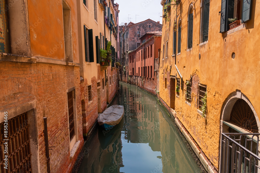 Traditional narrow canal street with gondolas and old houses in Venice, Italy. Architecture and landmarks of Venice. Beautiful Venice postcard.