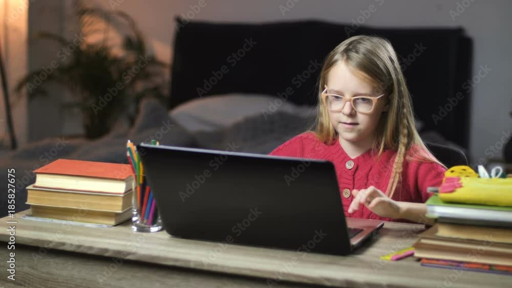Smiling school girl surfing net on laptop at home