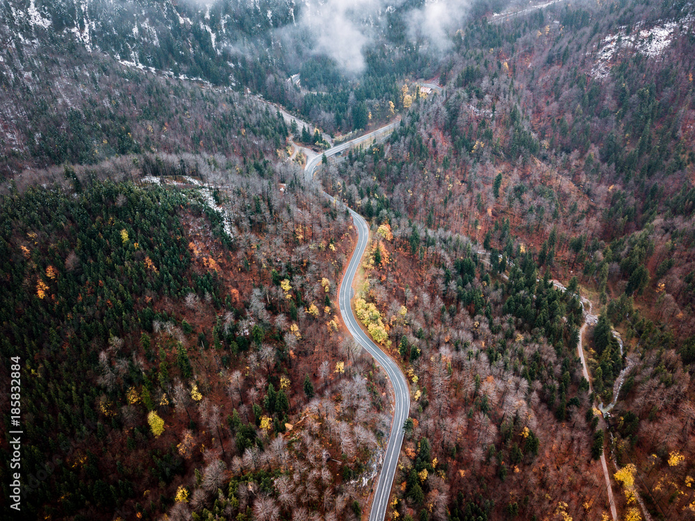 Winding serpentine mountain Road through a german forest during autumn with orange and yellow fall colors Winding serpentine mountain Road through a german forest during autumn with orange and yellow fall colors