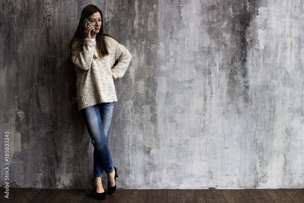 a young woman in a beige cardigan, jeans and black heels