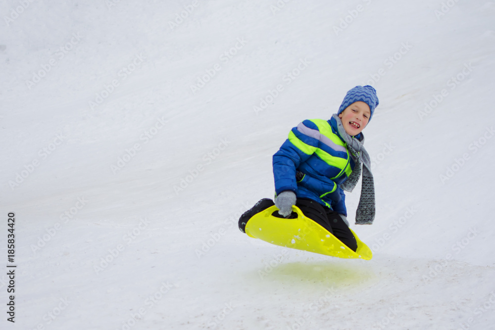 Kid slides down a hill on plate for driving on snow