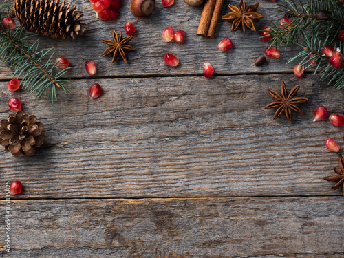 Pomegranate spruce branches star anise nuts, cinnamon and winter spices on wooden background, Rustic style Copy space