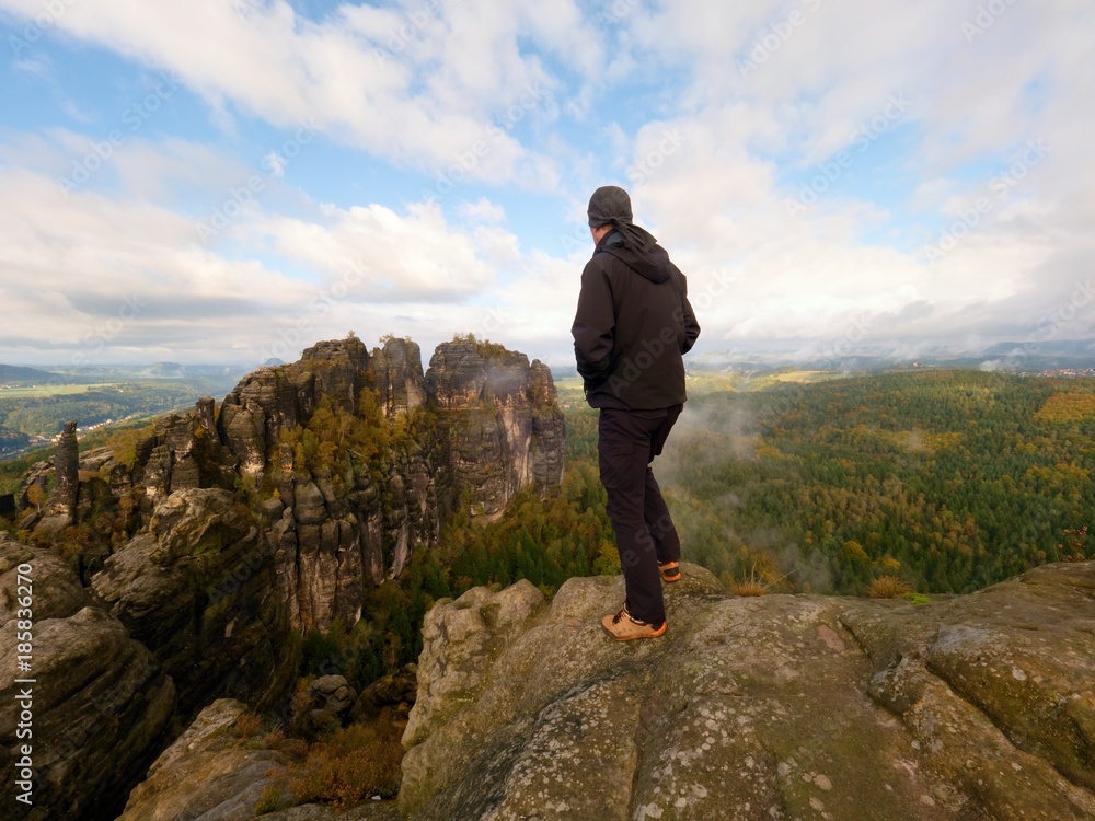 Hiker on rock end above valley. Man watch over misty and autumnal morning valley to bright morning nowhere. Hiker on rock end above valley. Man watch over misty and autumnal morning valley to bright morning nowhere.