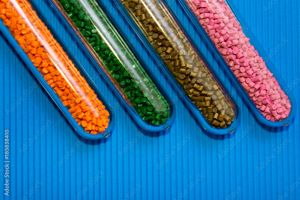 Plastic pellets .Polymeric dye in test tubes on blue corrugated background.Chemical background with plastic pellets Plastic pellets .Polymeric dye in test tubes on blue corrugated background.Chemical background with plastic pellets