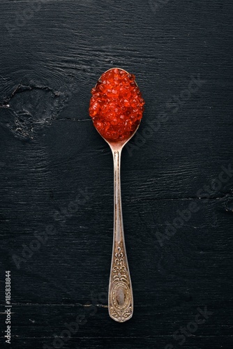 Spoon with red caviar on a wooden background. Top view. Free space for text.