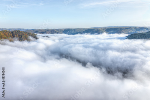 Mountains and fog, mist clouds in morning floating above forest trees, covering, blanketing valley in Grandview Overlook, West Virginia