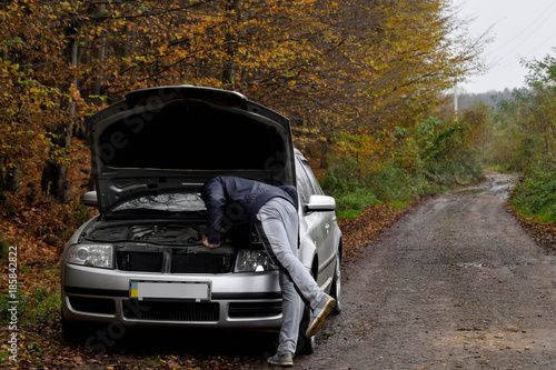 Men spection He opened the hood Broken car on the side See engines that are damaged or not. photo