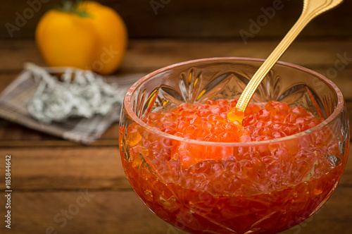 Red caviar in glass jar with gold spoon close up. Sea food. Healthy eating. Diet. Wooden rustic background. Selective focus. Top view