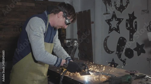 Blacksmith cuts iron details via plasma cutter at his workshop, slow motion. photo