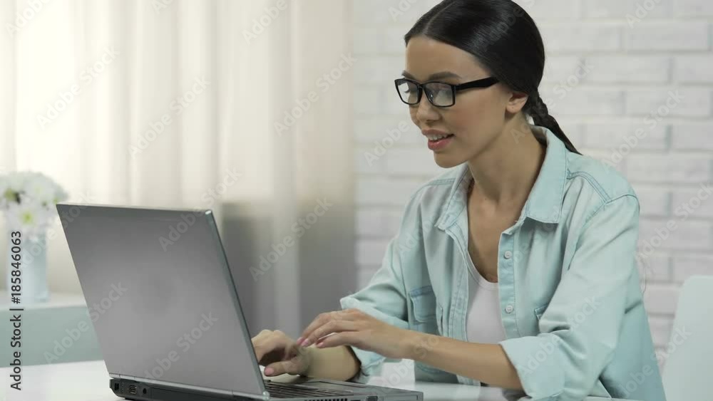 Asian woman in glasses chatting in social network, smiling and answering message Asian woman in glasses chatting in social network, smiling and answering message