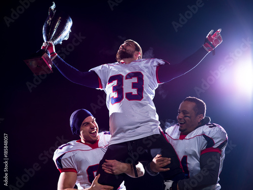 american football team with trophy celebrating victory