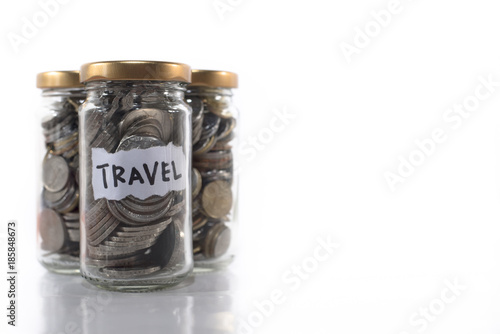 coins in a glass jar labeled   TRAVEL   isolated on a white background.Saving money for holidays and vacations. Saving concept and Travel concept.