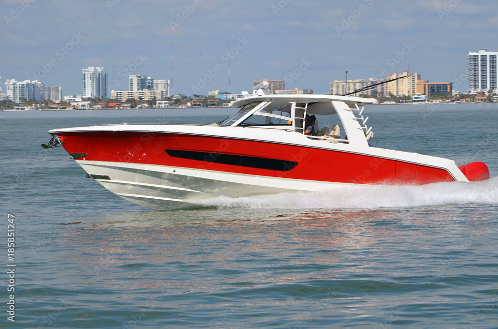 Fototapeta premium Well appointed sports fishing boat, red with white trim,cruising on the florida intra-coastal waterway off Miami Beach.